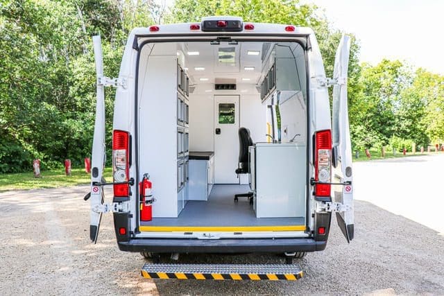Fourgon de clinique médicale mobile avec vue sur l'intérieur d'un espace de bureau lumineux et propre depuis l'arrière avec les portes ouvertes