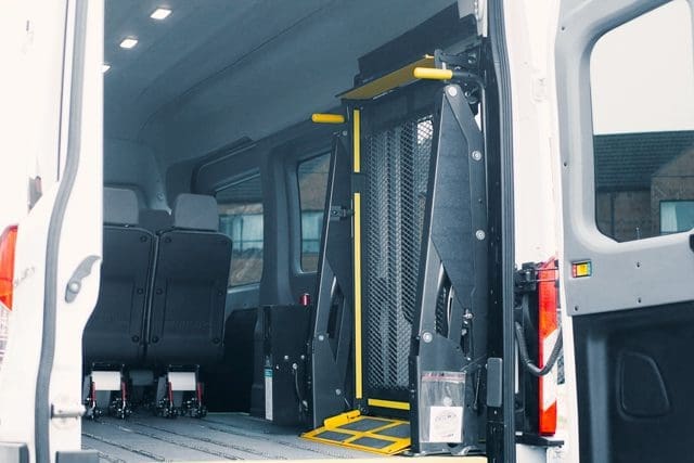 Ford Transit T6 rear doors open, showing BraunAbility wheelchair lift and seats