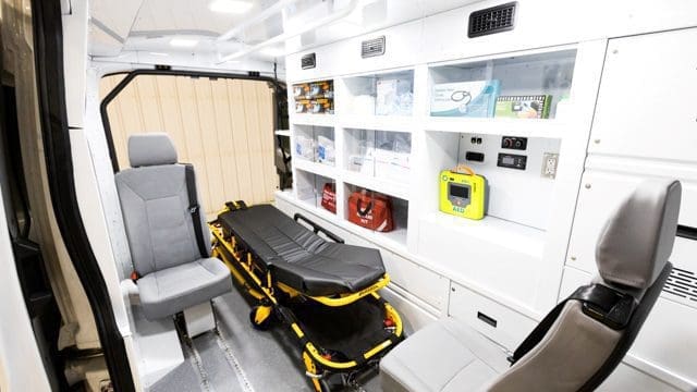 Intérieur d'un fourgon NEMT avec armoires et brancards en aluminium